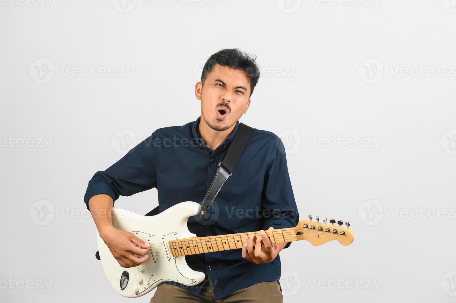 ritratto di giovane asiatico uomo nel blu camicia con elettronico chitarra isolato su bianca sfondo foto