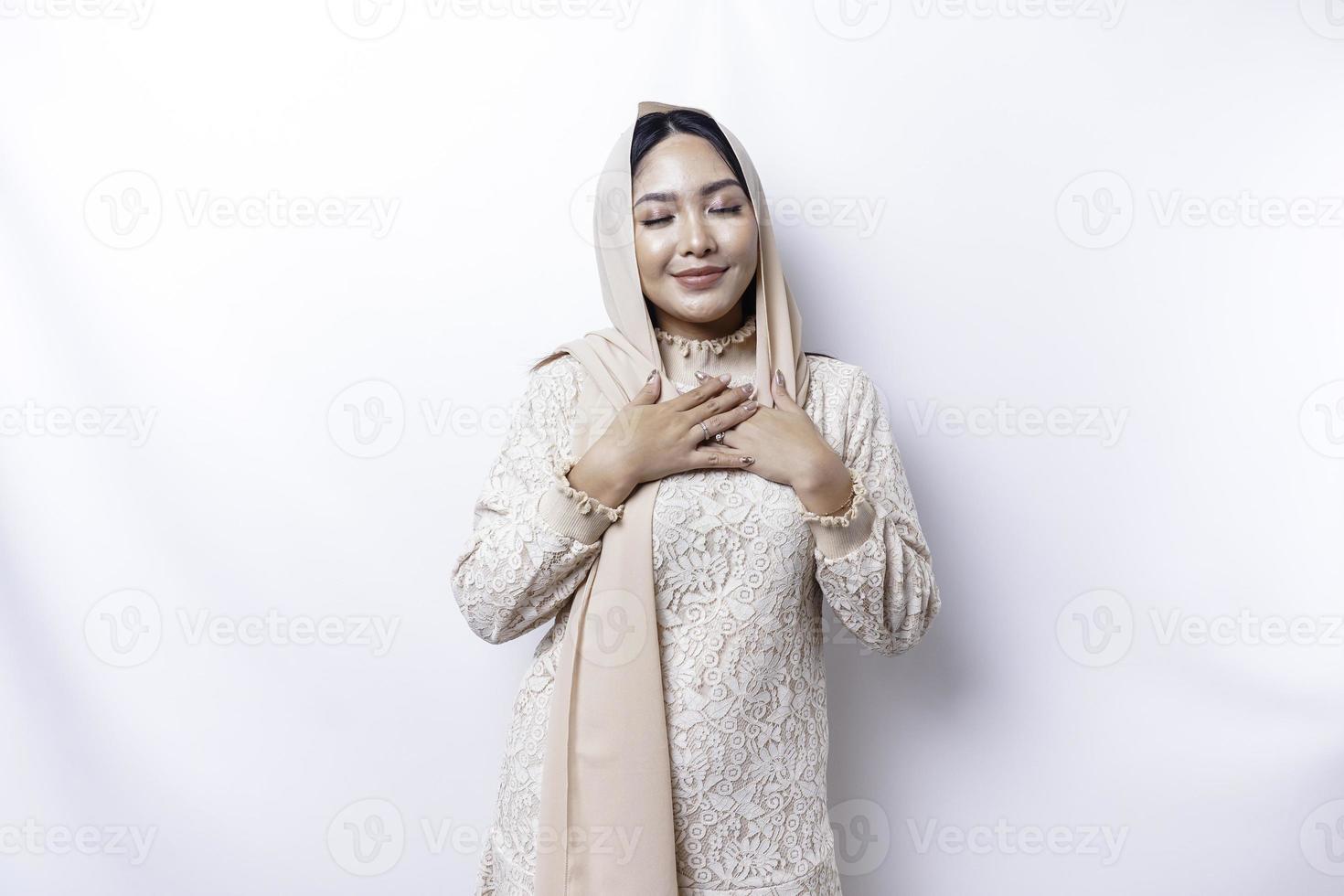 contento memore grato giovane asiatico musulmano donna con sua mano su sua il petto sorridente isolato su bianca sfondo foto