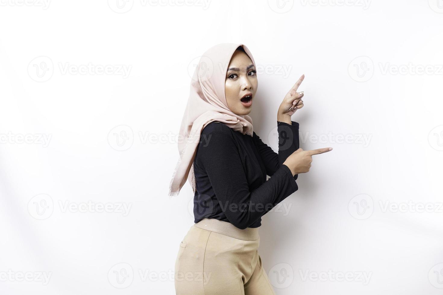 scioccato asiatico musulmano donna puntamento a il copia spazio su accanto suo, isolato di bianca sfondo foto
