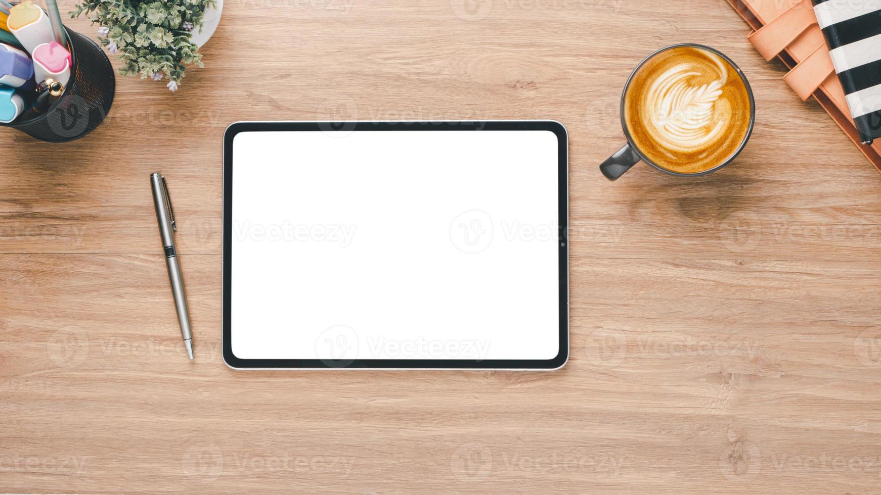 di legno scrivania posto di lavoro con vuoto schermo tavoletta, penna, taccuino e tazza di caffè, superiore Visualizza con copia spazio. foto