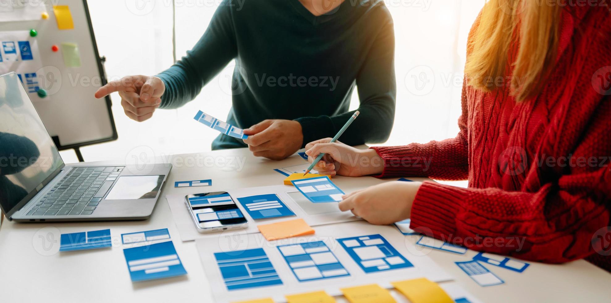 vicino su Visualizza di ui sviluppatore squadra di brainstorming su loro progetto con computer portatile, smartphone e digitale tavoletta. creativo digitale sviluppo agenzia. foto