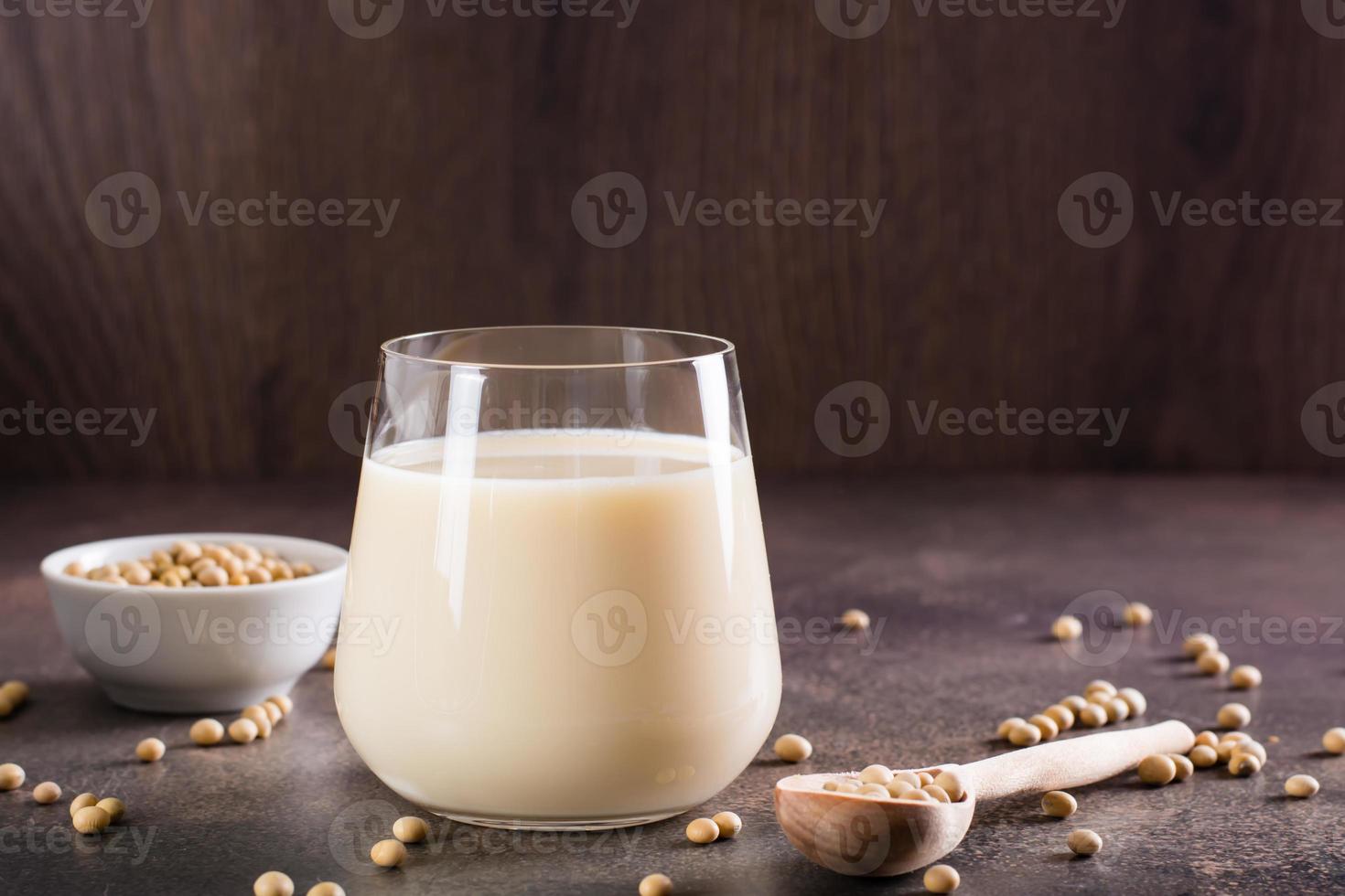 soia latte nel un' bicchiere e semi di soia nel un' ciotola su il tavolo. lattosio gratuito bere. foto