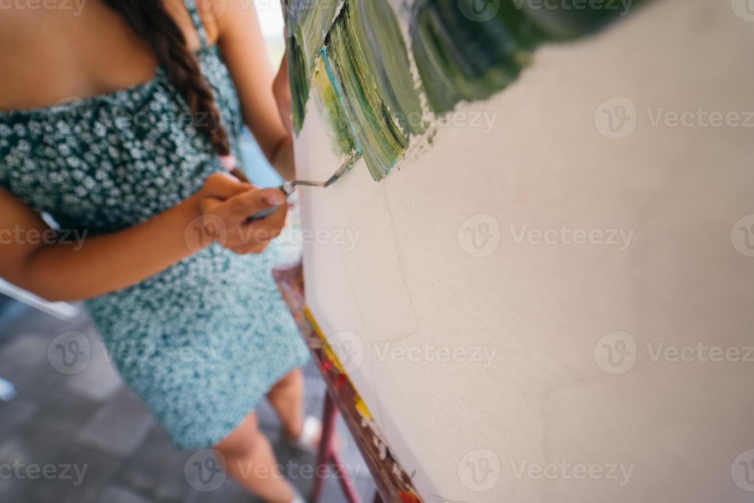 giovane donna artista vernici con un' spatola su il tela foto