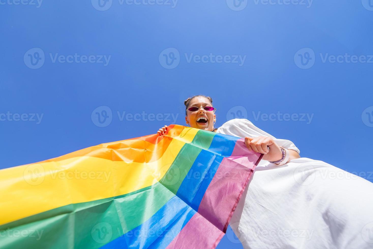 un' giovane donna si sviluppa un' arcobaleno bandiera contro il cielo foto