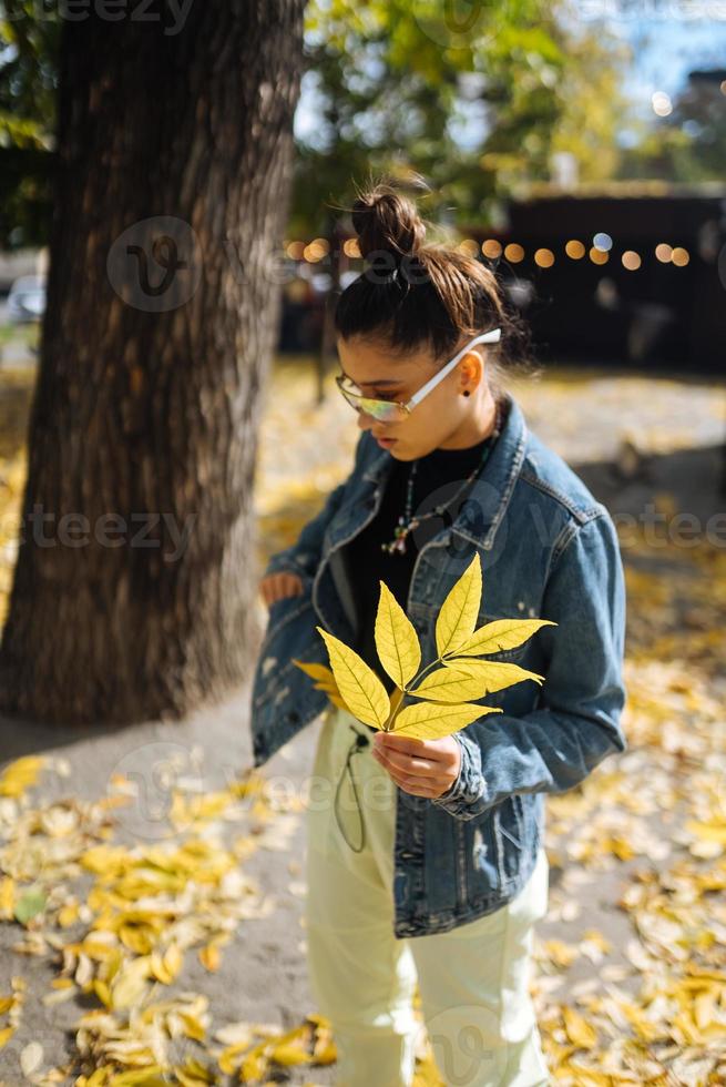 un' donna nel un autunno parco detiene un' giallo foglia foto