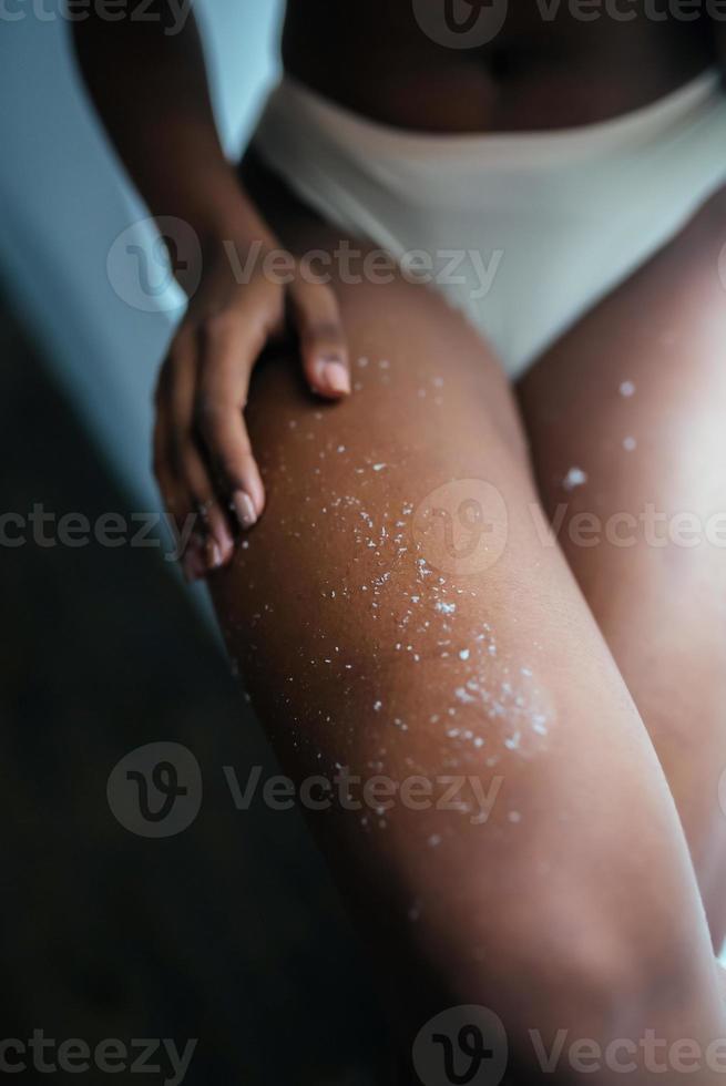 giovane bellissima africano americano ragazza l'applicazione mettendo macchia su gambe foto