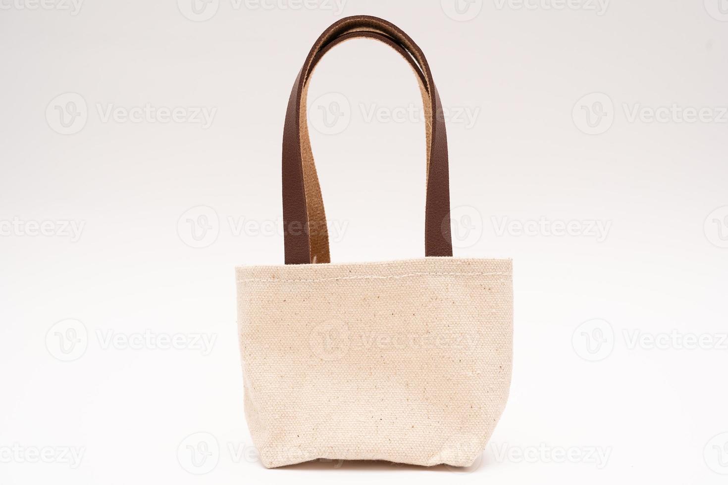 piccolo pieno tela Borsa con cravatte, riutilizzabile eco Borsa. vuoto piccolo cotone Borsa con corda su bianca sfondo. foto