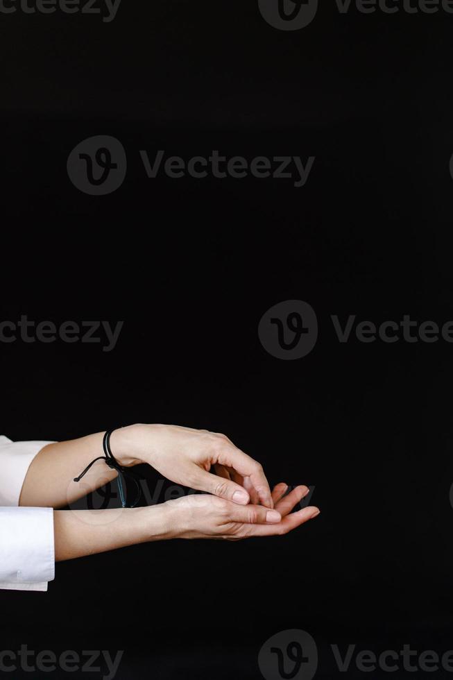 Da donna mani con un' braccialetto su un' nero sfondo foto