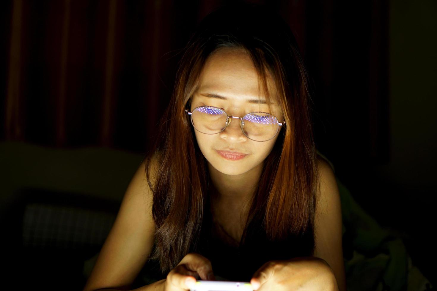 asiatico donna indossare bicchieri per Visualizza il computer nel Basso leggero orologio film in linea foto