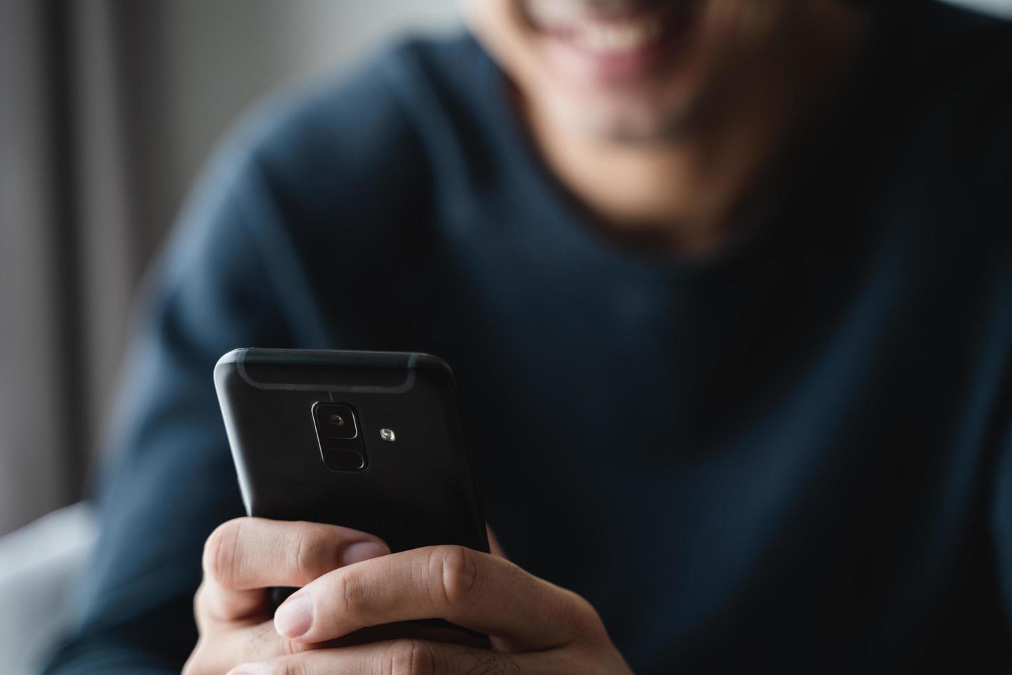 uomo utilizzando smartphone su divano nel vivente camera a casa, ricerca dati e sociale media su Internet. foto