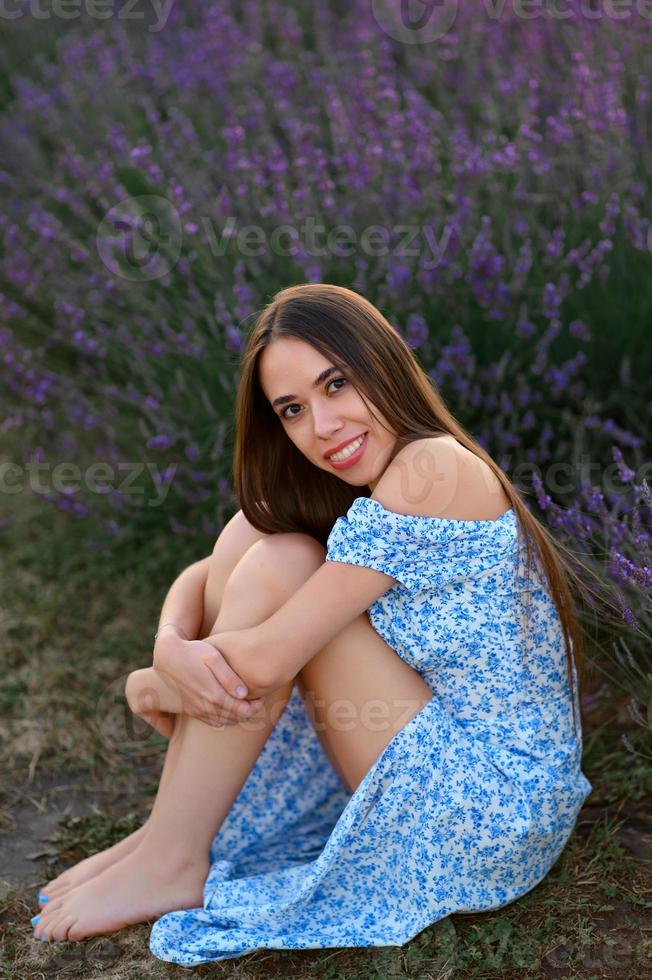 attraente snello contento ragazza nel un' blu vestito nel un' lavanda campo a tramonto. foto