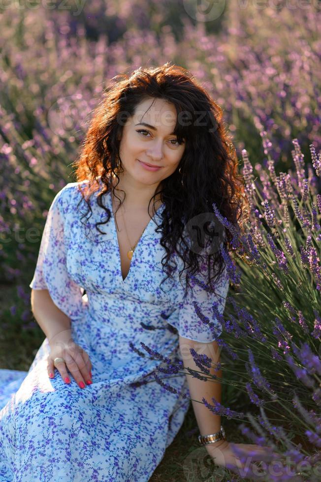 ritratto di un' contento donna nel un' blu vestito godendo un' soleggiato estate giorno nel un' lavanda campo. fresco aria, stile di vita. foto