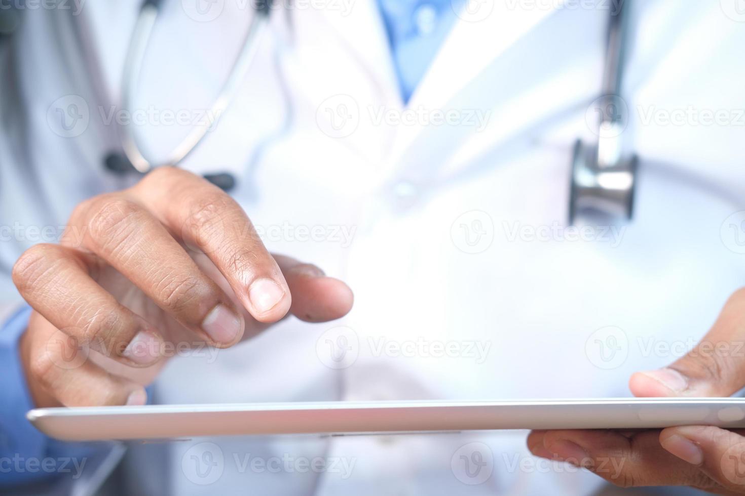medico in camice bianco sta usando una tavoletta digitale foto