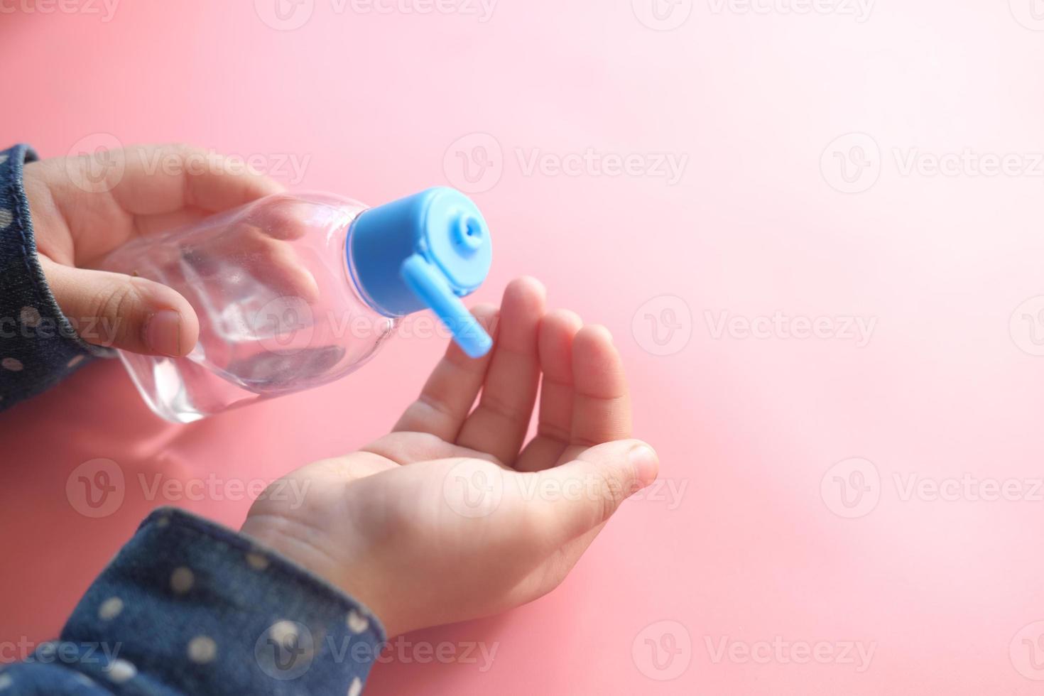 bambino che utilizza liquido disinfettante foto