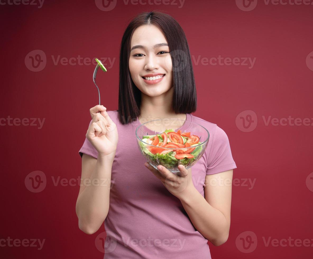 giovane asiatico donna mangiare insalata su sfondo foto