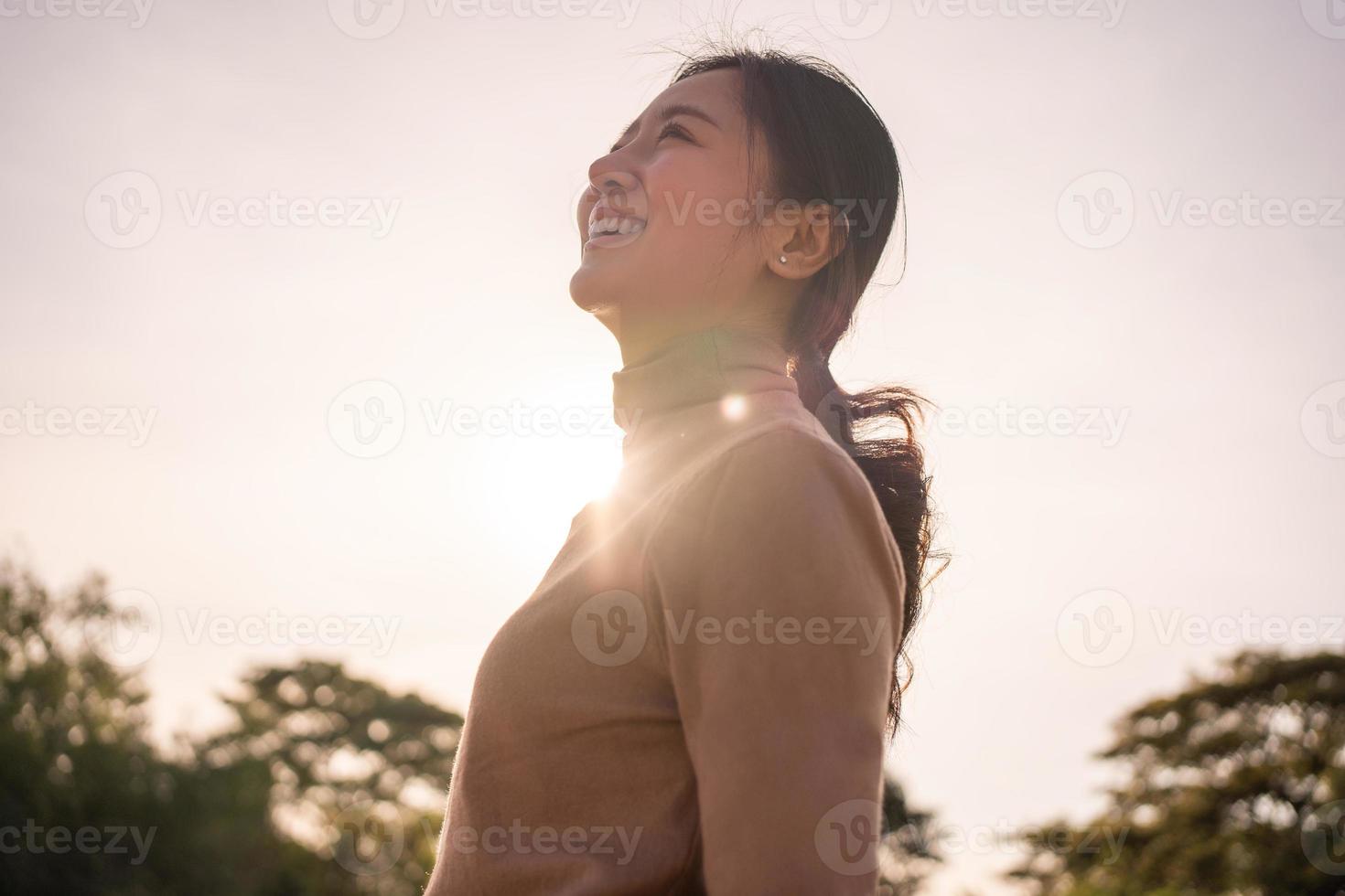 contento asiatico donna sorridente all'aperto lei sembra su a il cielo foto