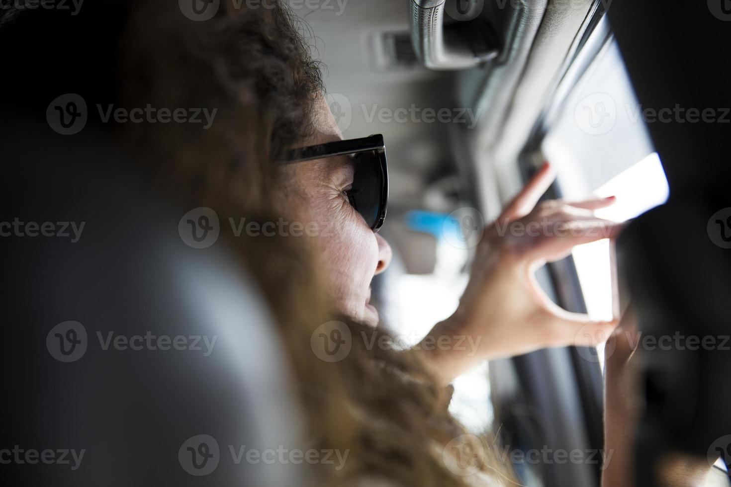 giovane donna che scatta una foto con il telefono cellulare dall'interno di un veicolo durante un viaggio