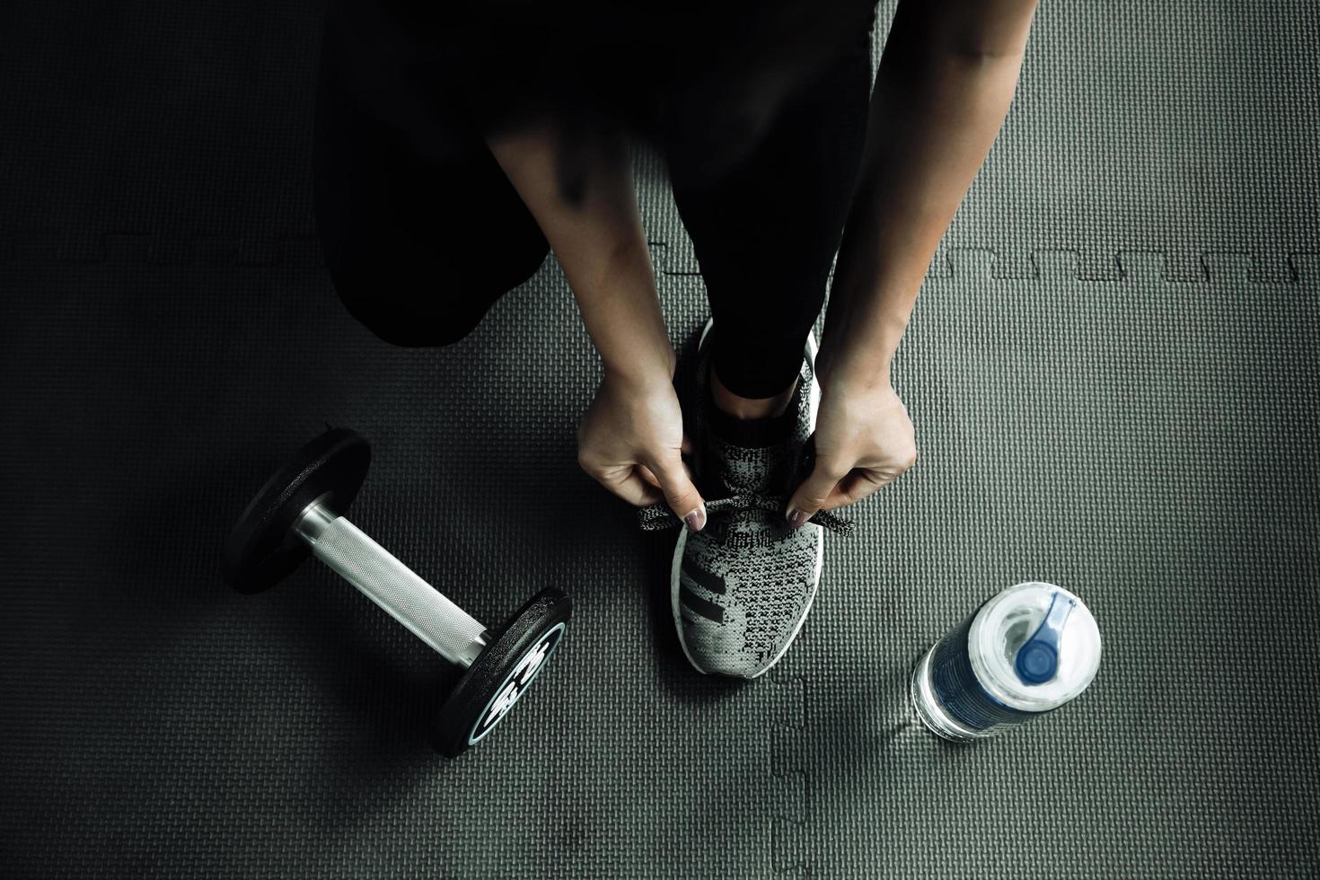 donna che lega i lacci delle scarpe. Close up del corridore di fitness sport femminile si prepara per fare jogging in palestra foto