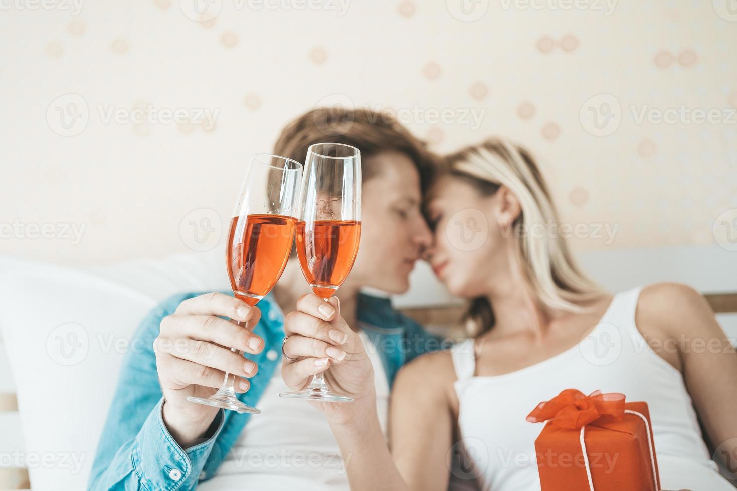 coppia felice che beve vino in camera da letto foto