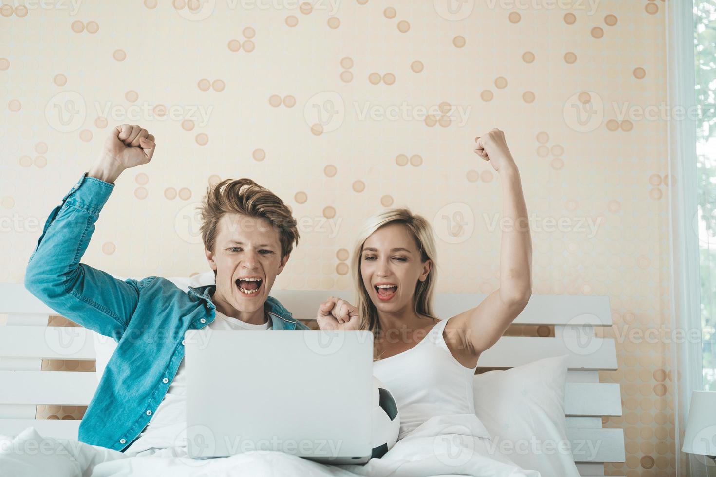 coppia felice guardando il calcio di calcio sul letto foto