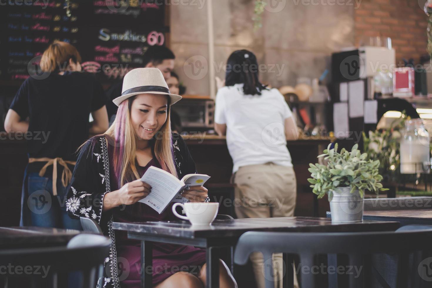 donna d'affari felice leggendo un libro mentre vi rilassate al bar foto