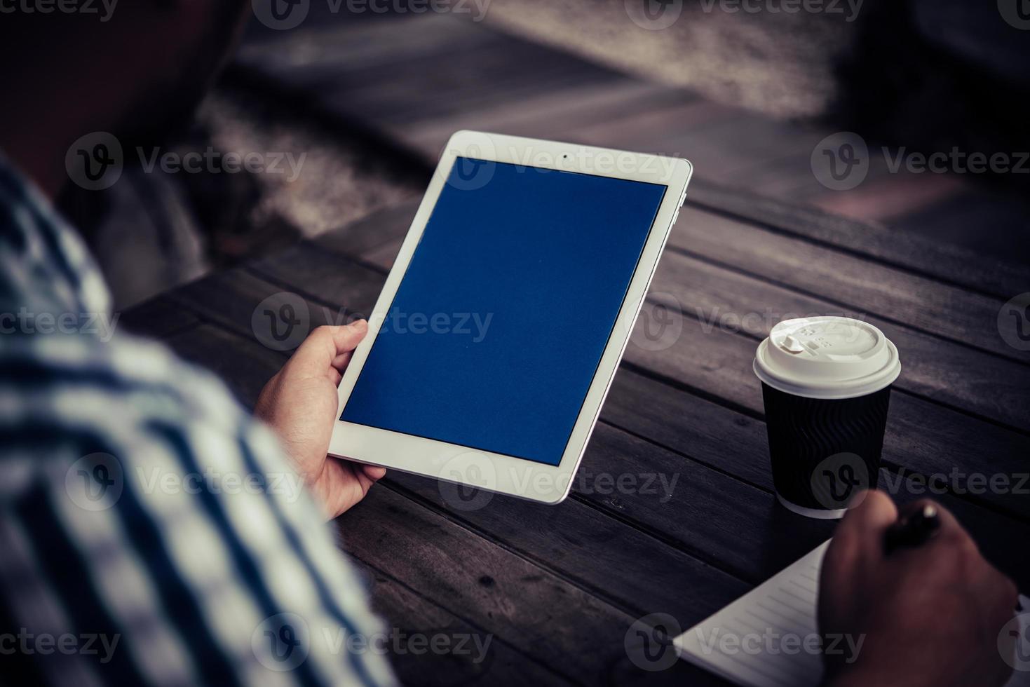 giovane uomo utilizzando la tavoletta digitale mentre beve il caffè seduto nel giardino di casa foto