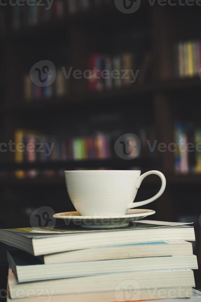 tazza di caffè e pila di libri sulla tavola di legno foto