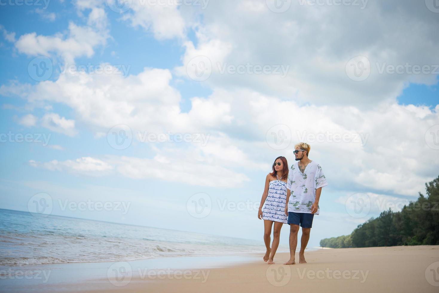 giovane coppia felice camminando sulla spiaggia sorridendo foto