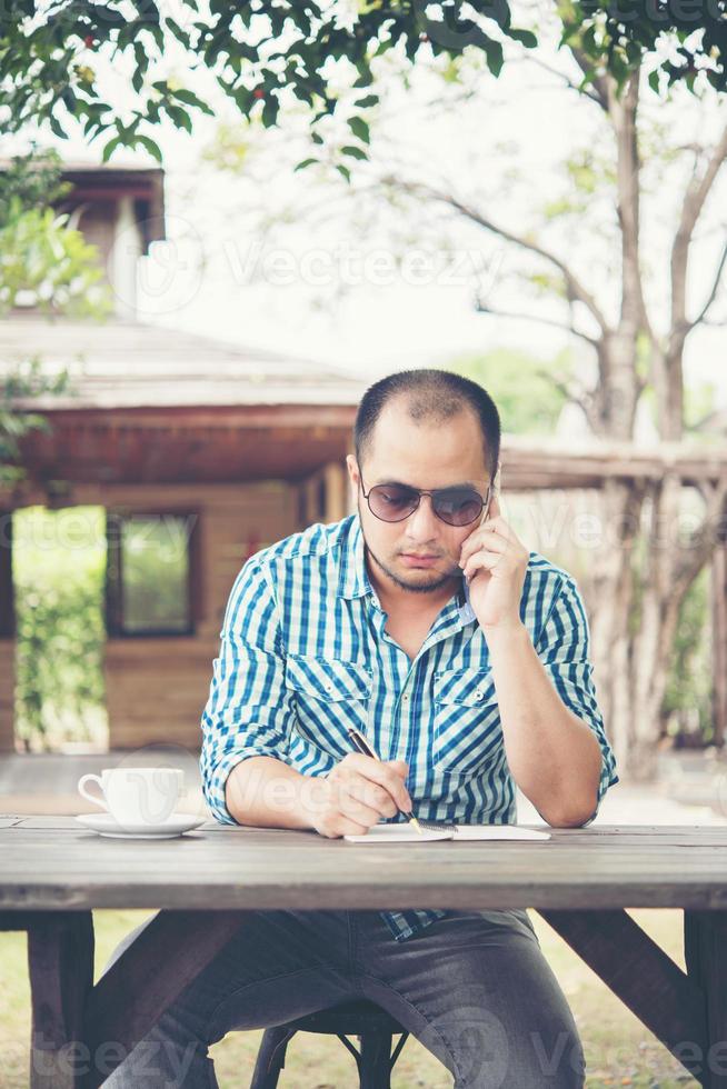 giovane imprenditore utilizza lo smartphone mentre si lavora nel giardino di casa foto