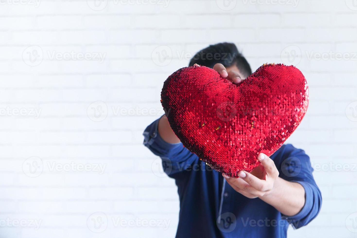 uomo che tiene un cuscino cuore lustrini foto