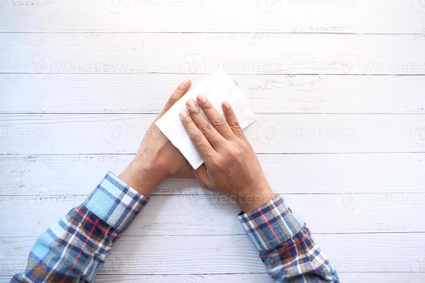 uomo che disinfetta le mani con un panno umido foto