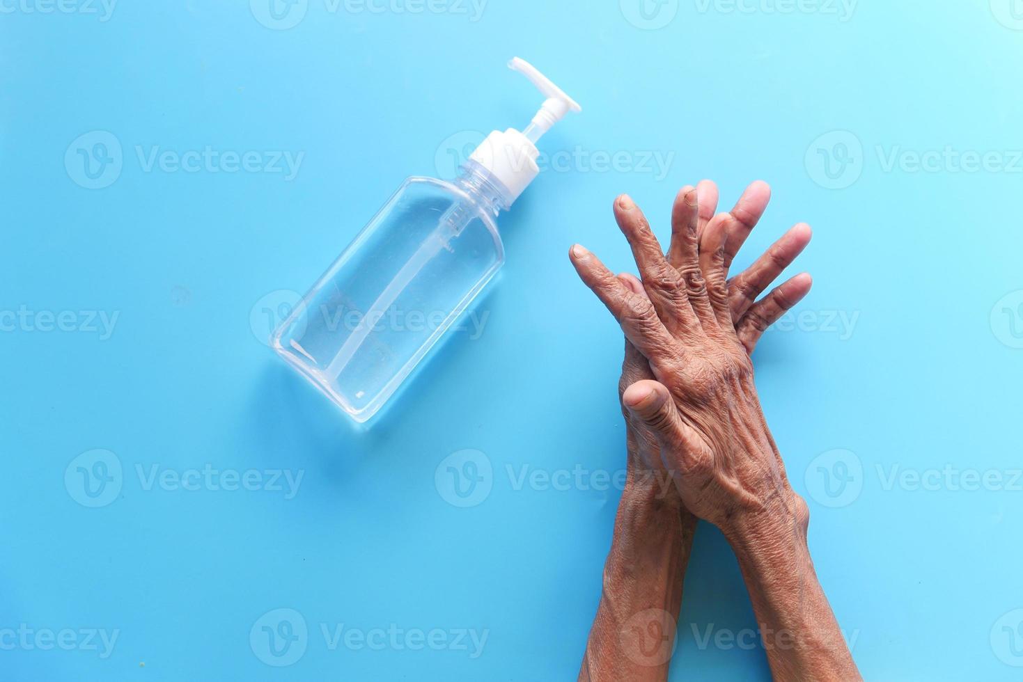 persona che utilizza un disinfettante per le mani su sfondo blu foto