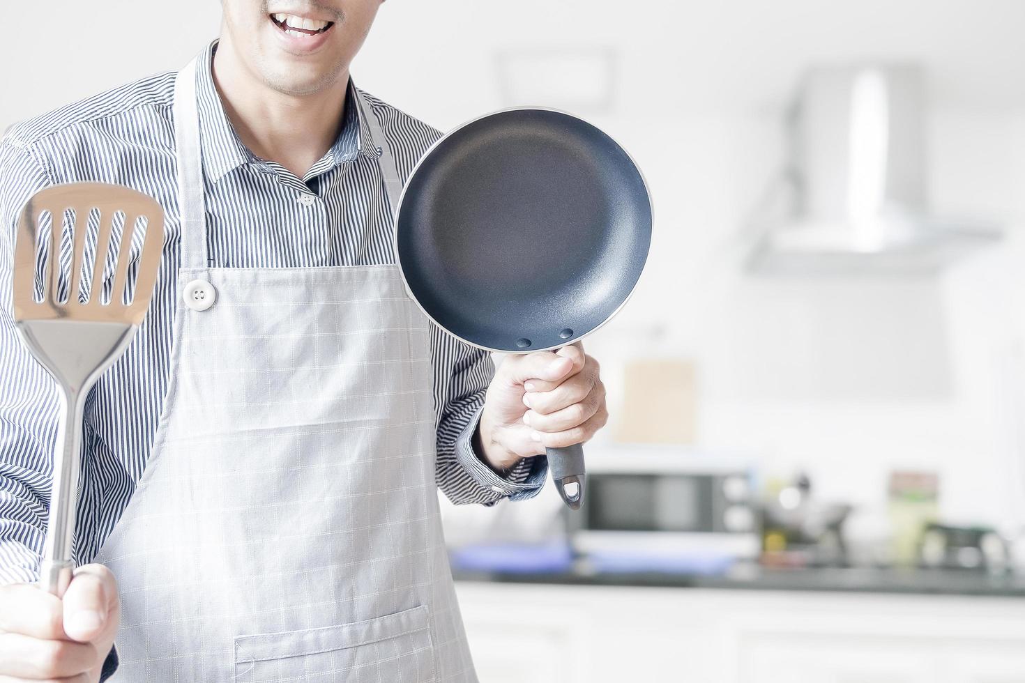 uomo che tiene una padella e una spatola foto