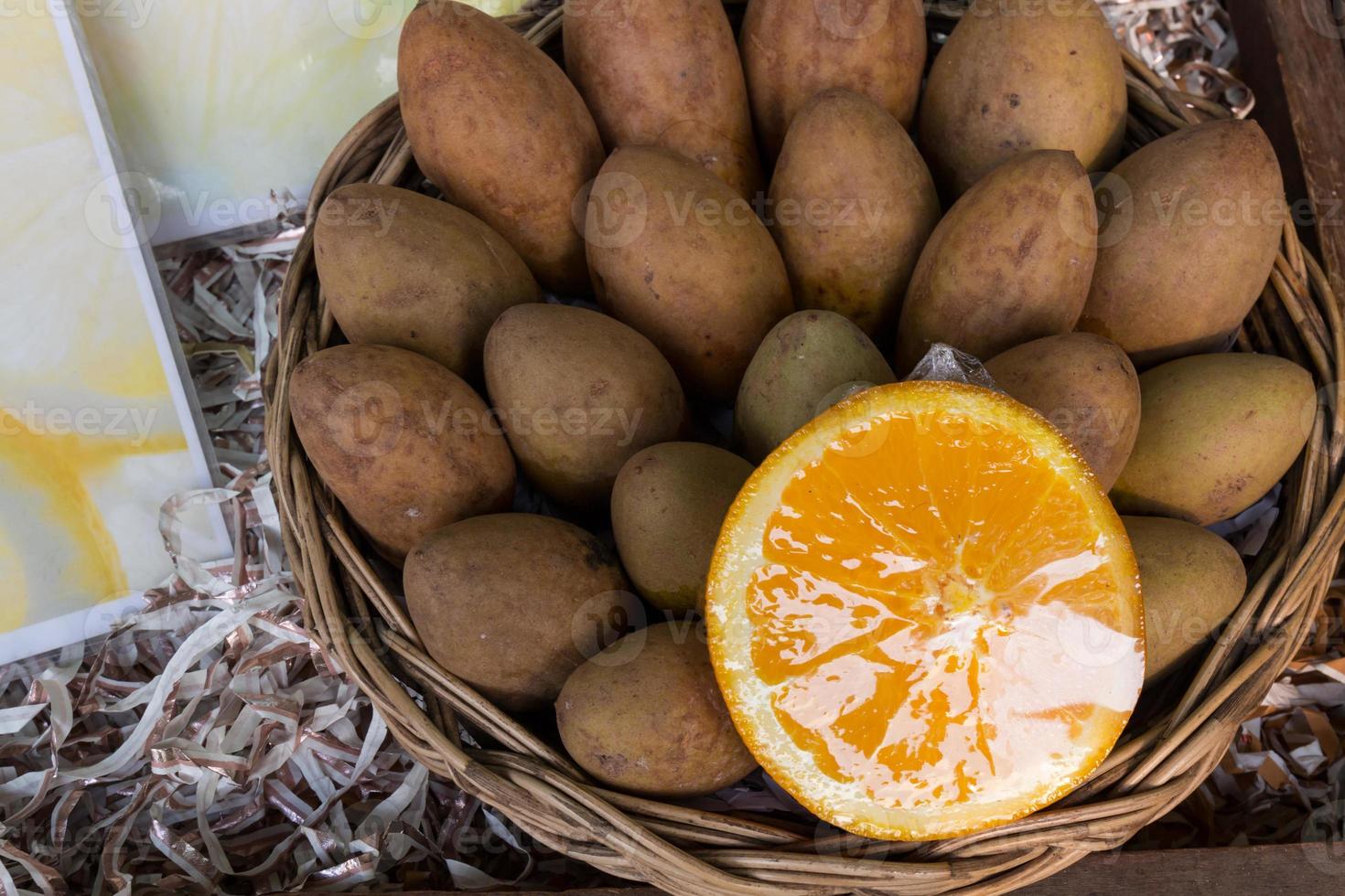 prugne sapodilla e arancia in un cesto foto