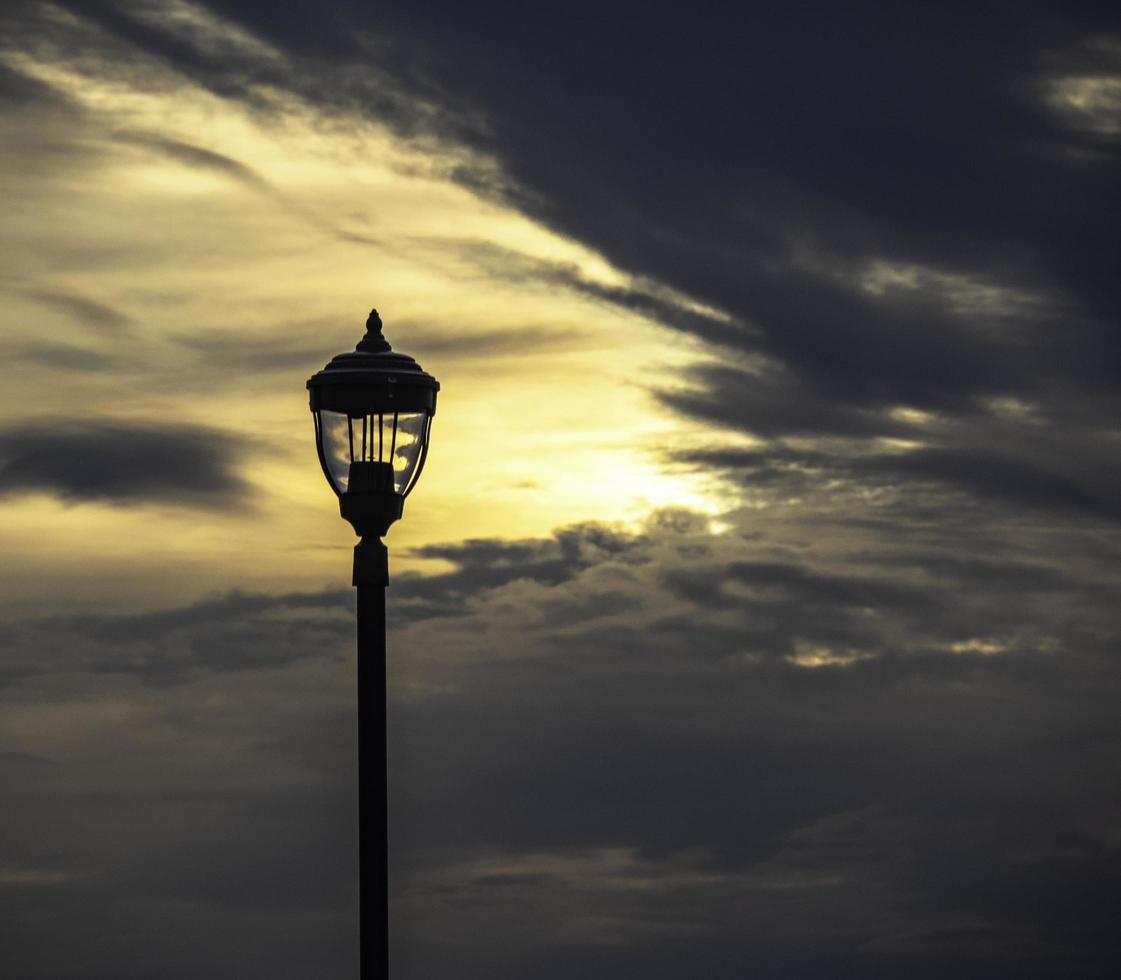 un lampione che si staglia all'alba in un cielo nuvoloso foto