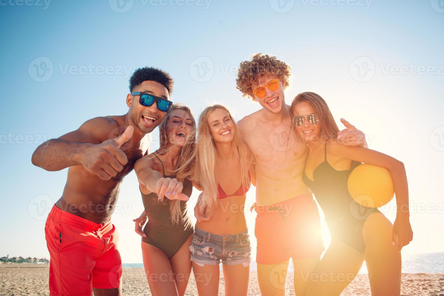 gruppo di amici giocando a spiaggia volley a il spiaggia foto