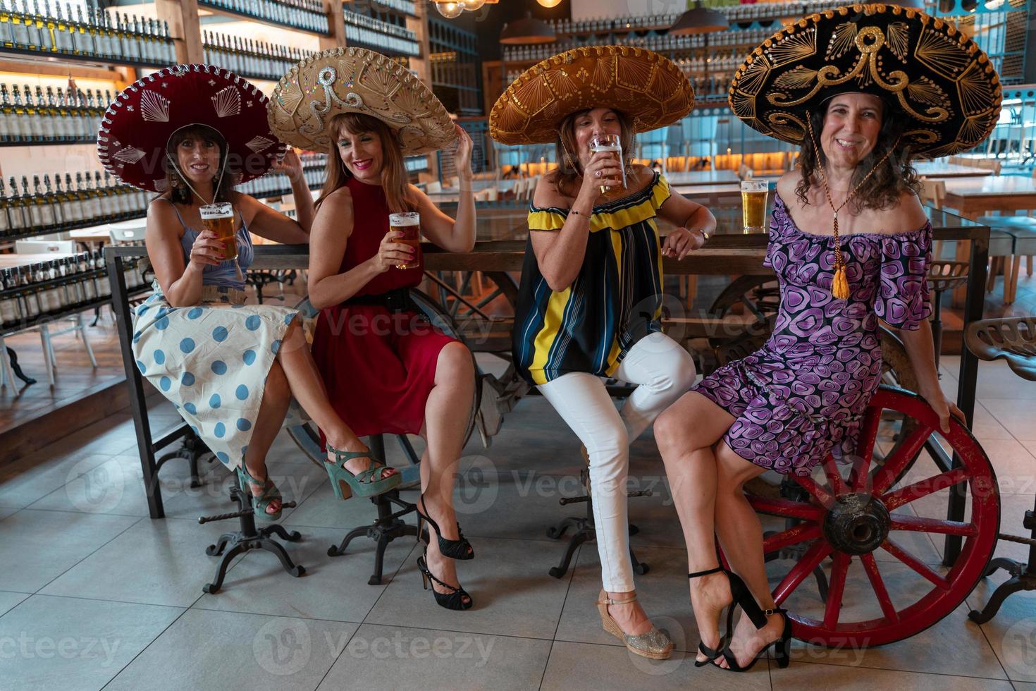 gruppo di maturo donne è potabile birra nel un' pub indossare sombreros foto