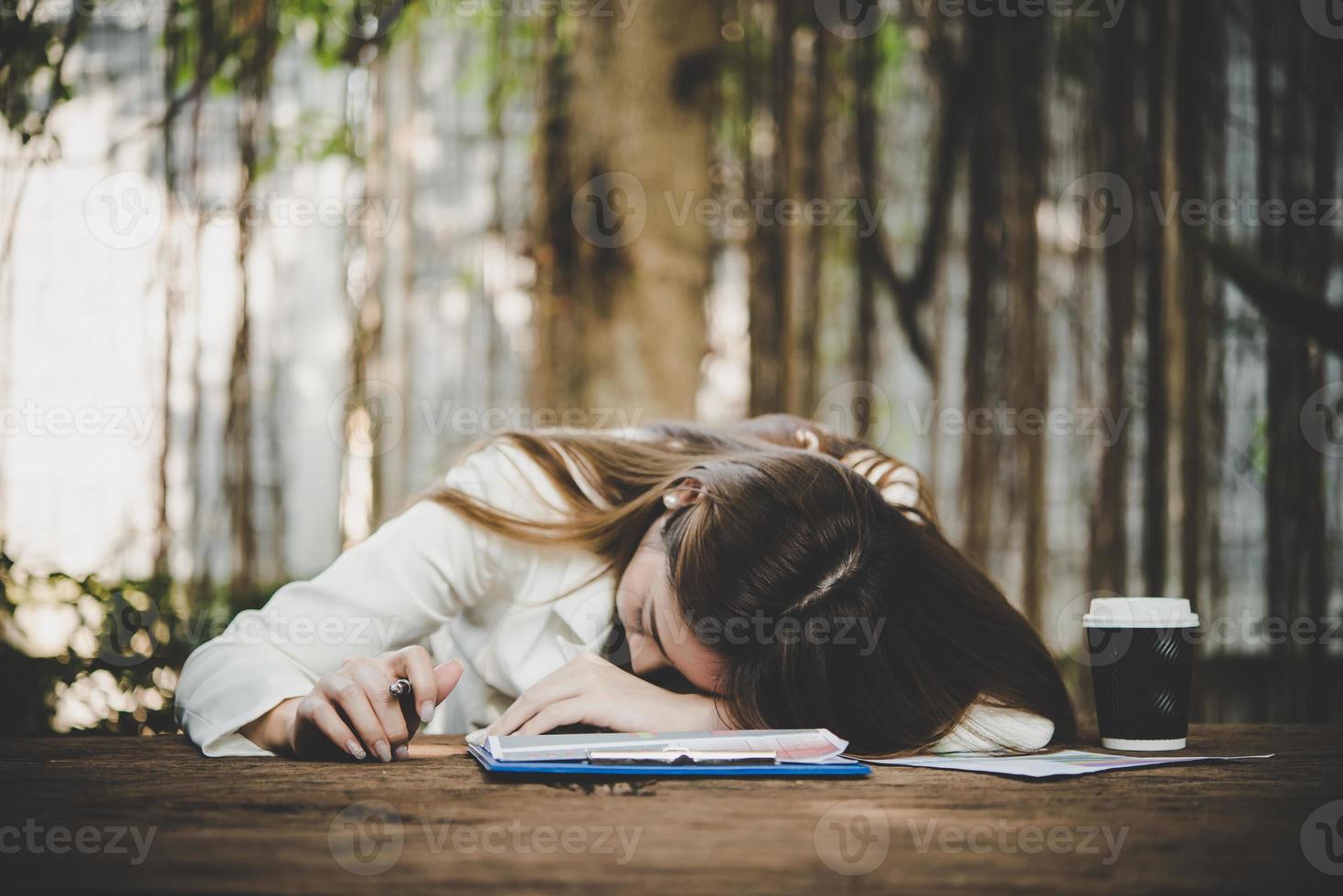 donna freelance stanca ed esausta che dorme sul computer portatile in ufficio foto