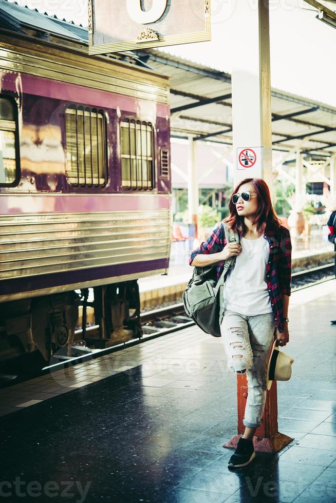 donna giovane hipster in attesa sul binario della stazione con lo zaino foto