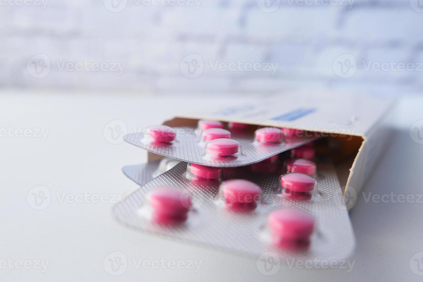 pillole rosa in confezioni blister in una scatola sul tavolo foto