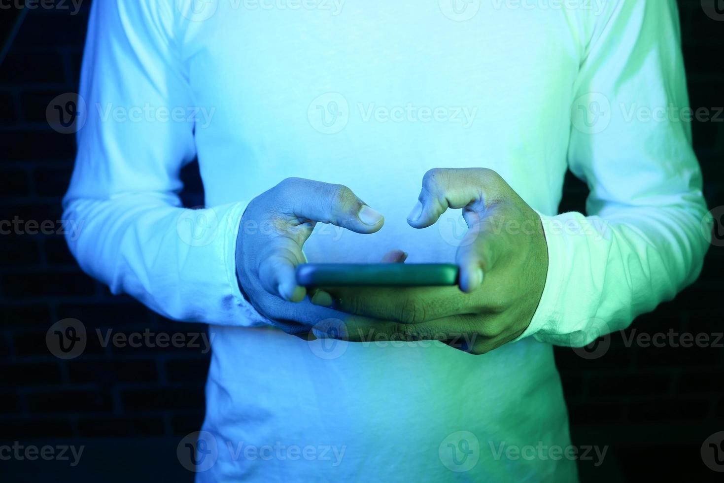 stretta di mano del giovane utilizzando uno smart phone di notte foto