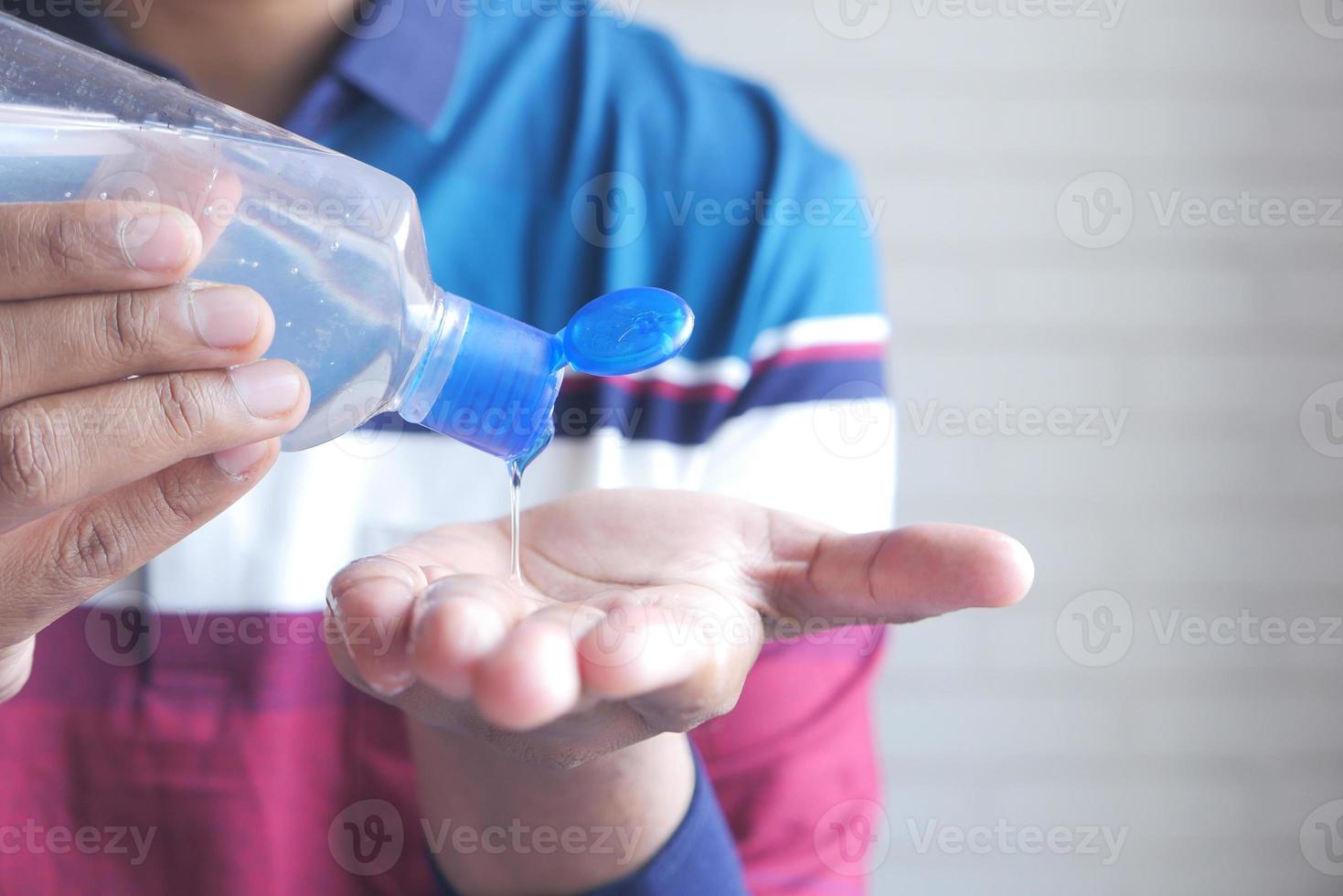 giovane che applica gel disinfettante per le mani foto