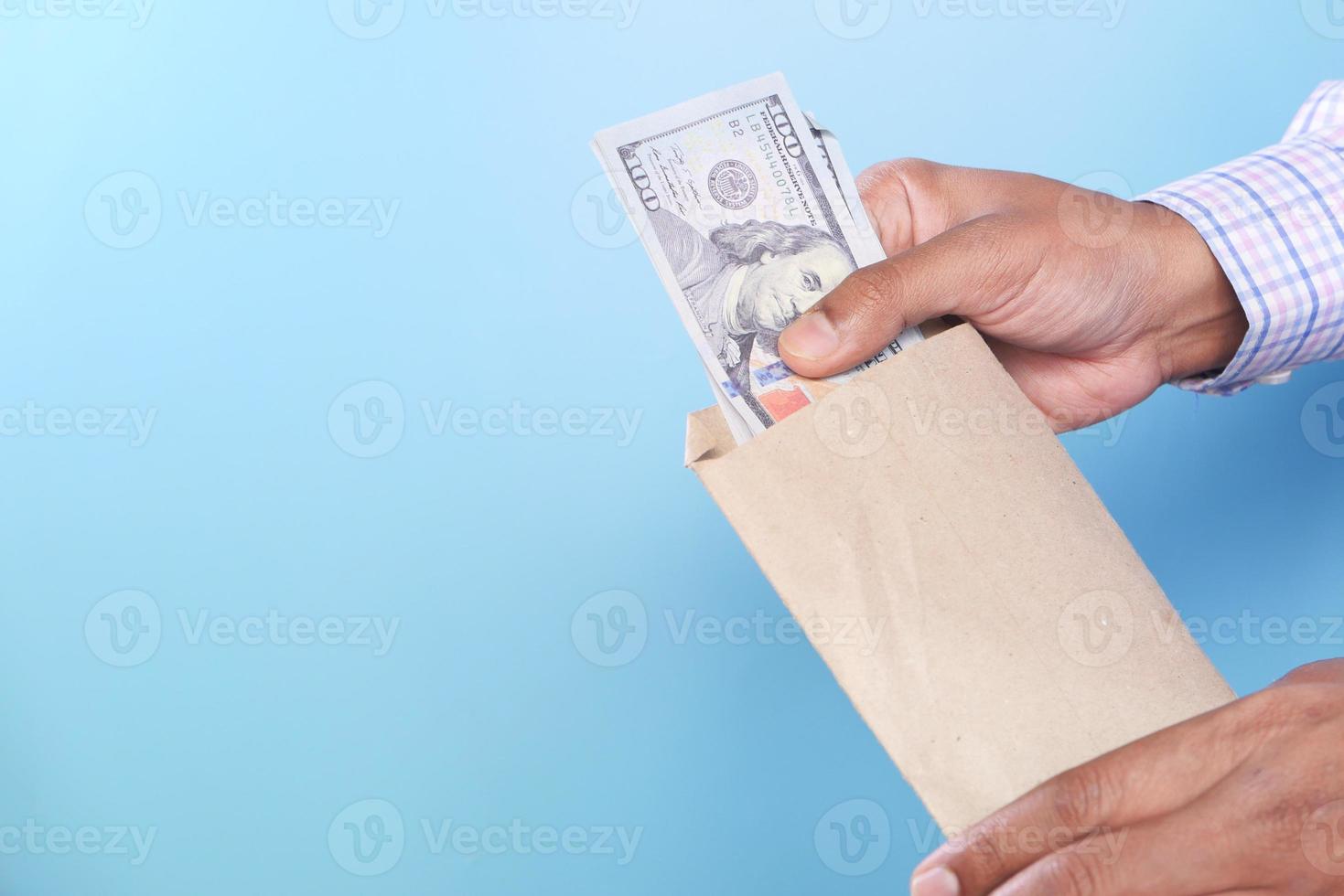 persona che mette banconote di grandi dimensioni in una borsa marrone foto