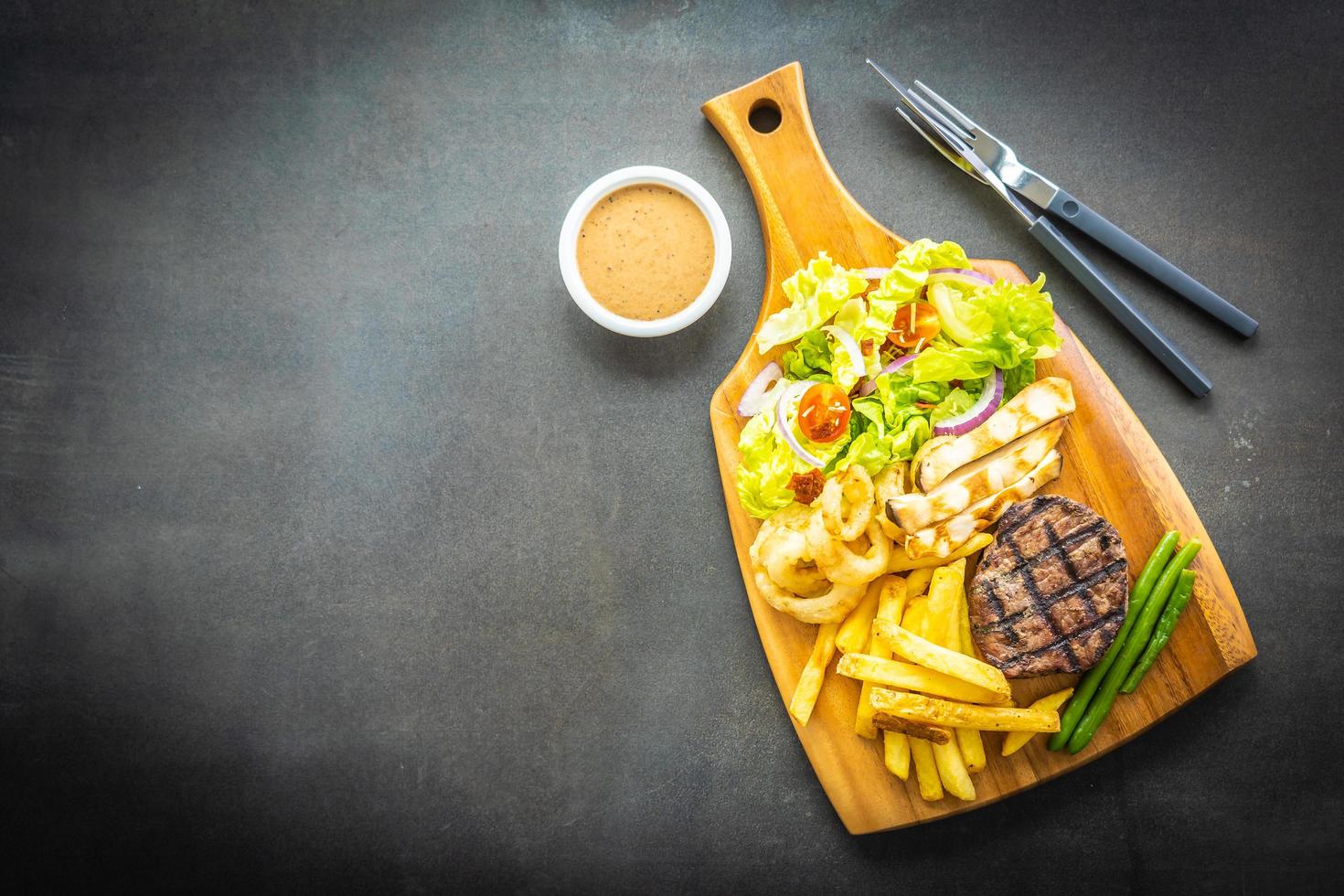 bistecca di manzo alla griglia con patatine fritte, salsa e verdure fresche foto