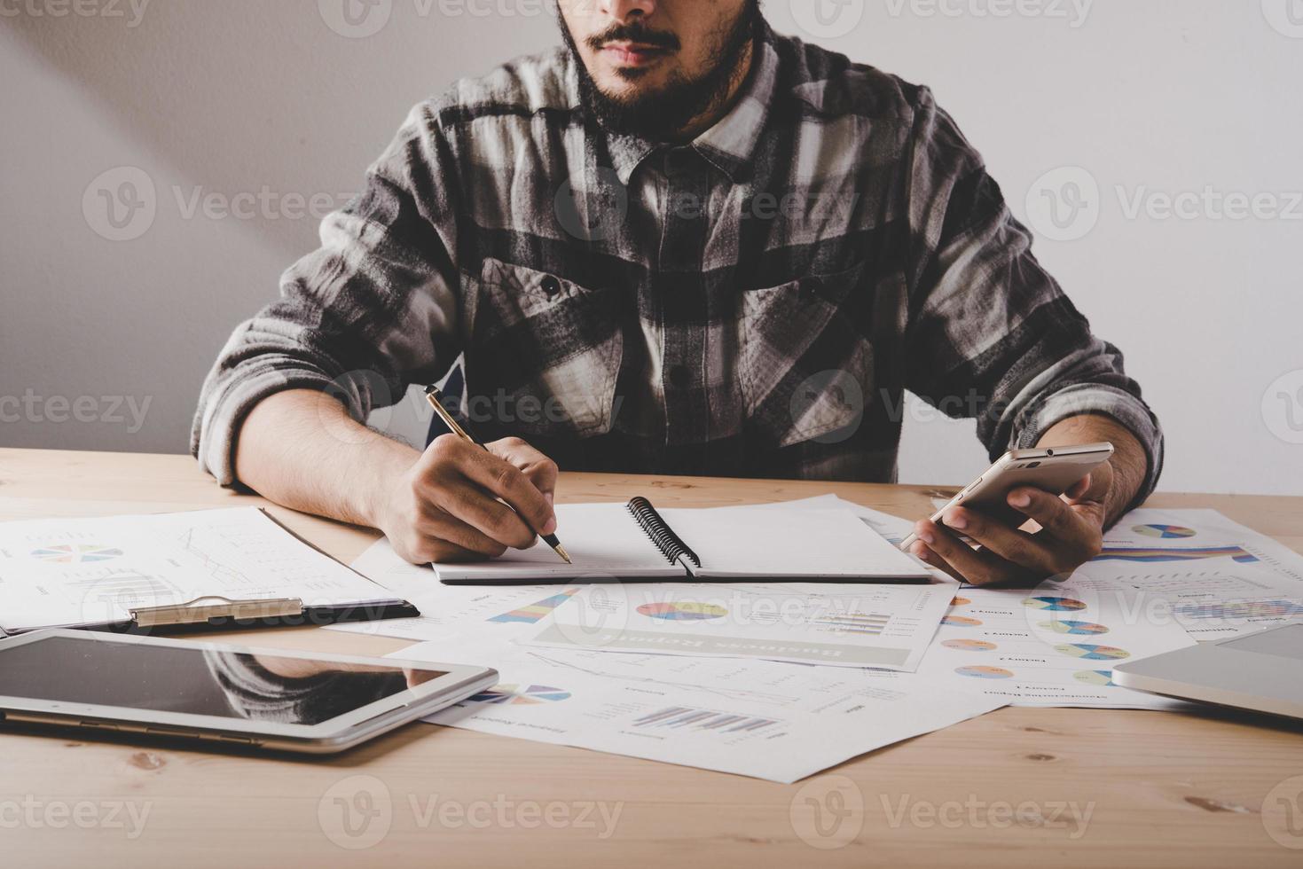 giovane imprenditore scrive in un notebook mentre si lavora l'analisi dei dati aziendali in ufficio foto
