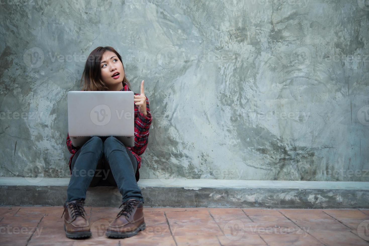 felice giovane donna pantaloni a vita bassa utilizzando il suo laptop mentre era seduto per terra foto