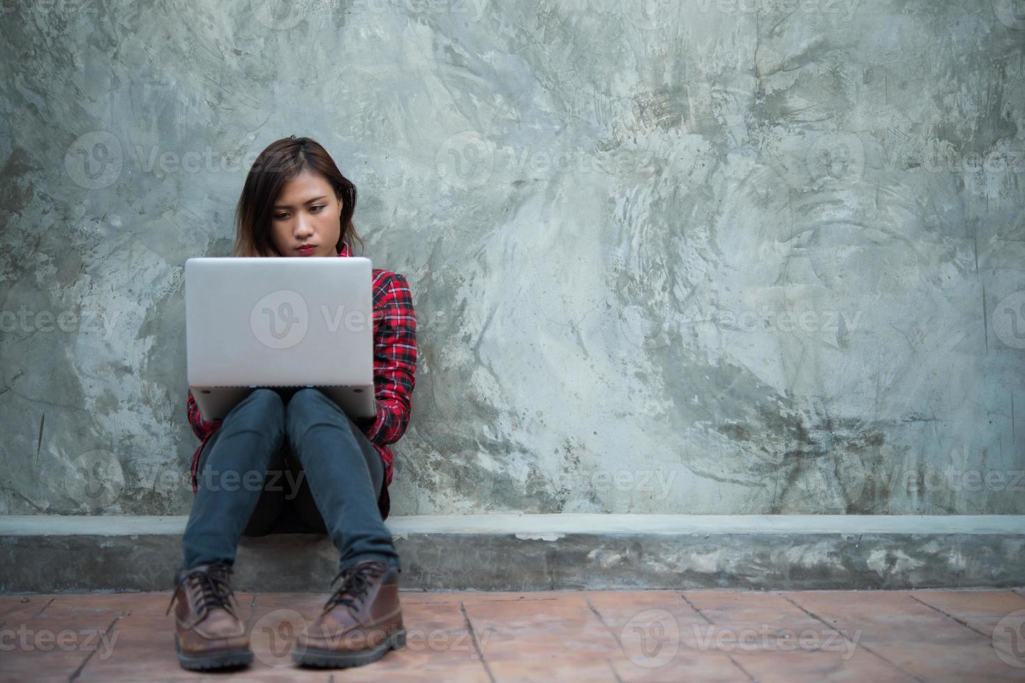 felice giovane donna pantaloni a vita bassa utilizzando il suo laptop mentre era seduto per terra foto