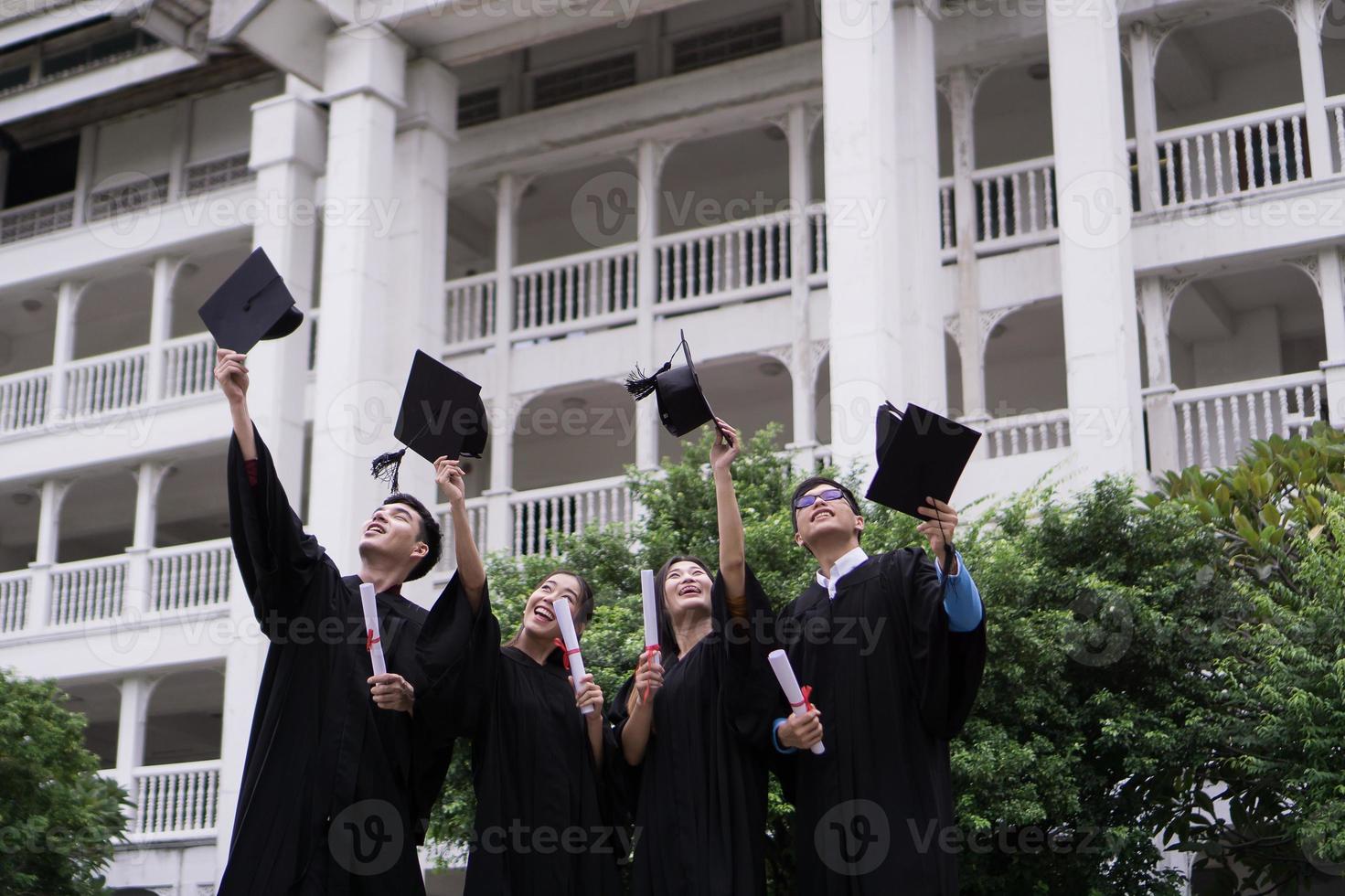 gruppo di studenti di successo che lanciano cappelli da laurea in aria e festeggiano foto