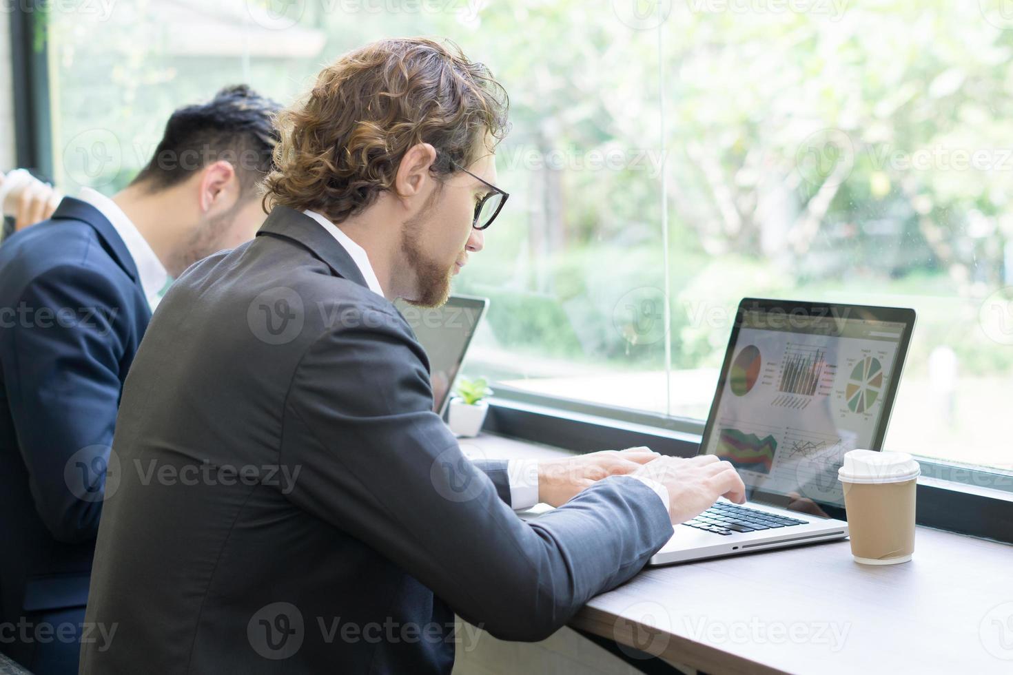 giovane uomo d'affari che lavora al computer portatile in ufficio foto