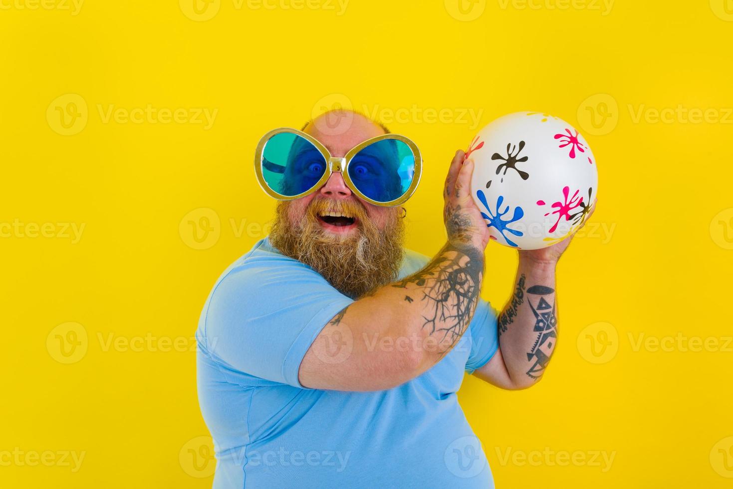 Grasso uomo con barba e occhiali da sole avere divertimento con un' palla foto